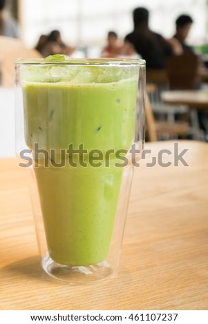 Green tea latte on transparent glass on brown wooden table - size view