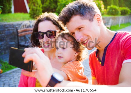 Young and happy family with a baby taking a selfie.