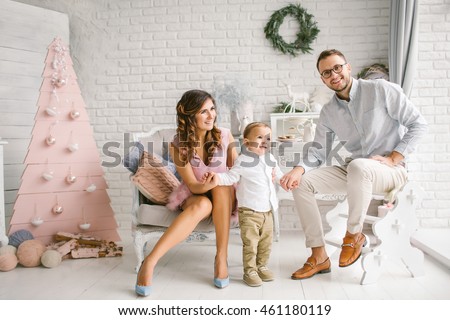 Happy father pretty mother and baby boy having fun in xmas decorated studio