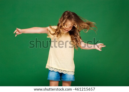 Young pretty girl dancing over green background.