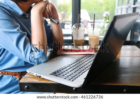 happy woman working with laptop and write pen on notebook on wooden desk office with coffee cup, internet of things lifestyle background