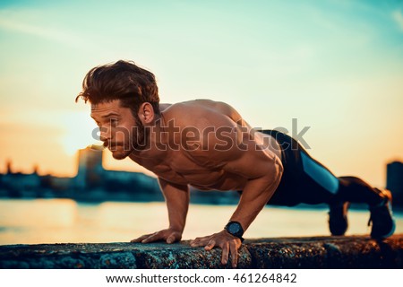 Picture of a young athletic man doing push ups outdoors.