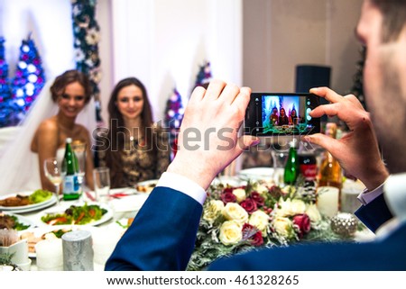 Groom taking picture of happy bride & bridesmaid at reception