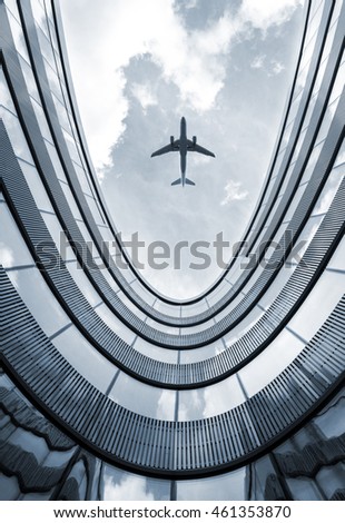 Modern architecture building with flying airplane in background. Low angle view blue colorized picture.