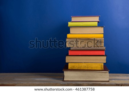 Books on grunge wooden table desk shelf in library. Back to school background with copy space for your ad text. Old hardback books with no labels, blank spine