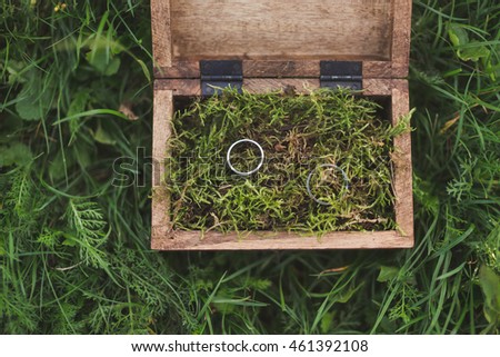 wedding rings in a wooden box filled with moss on the green grass