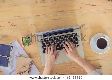 office desk mockup: laptop, smart phone, and cup of coffee and notebook with business financial graph on wooden background. View above shot. Vintage filter effect.