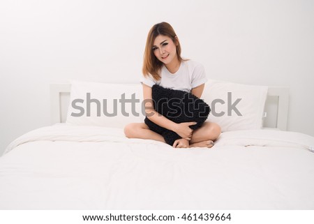 Asian woman sitting on white bed and smiling, happy time lifestyle concept.