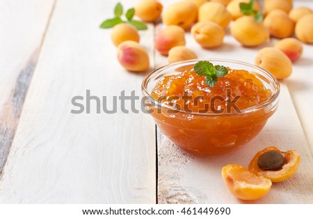 Apricot jam in a glass bowl, fresh apricots in a basket on a light wooden background Royalty-Free Stock Photo #461449690