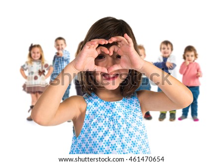 Girl making a heart with her hands  with many people behind