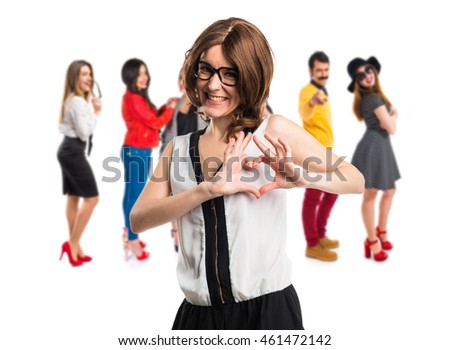 Brunette woman making a heart with her hands with many people behind