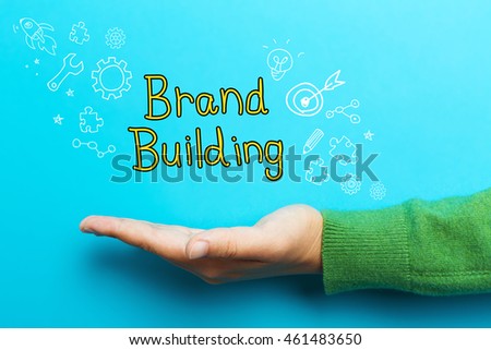 Brand Building concept with hand on blue background