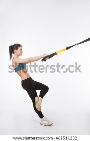 Picture of young beautiful woman training with suspension trainer sling isolated on white background. Upper body exercise concept.