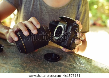 closeup of a young caucasian man taking out the lens of his reflex camera outdoors Royalty-Free Stock Photo #461573131
