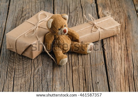 Valentine's day homemade gifts in craft paper with hearts tags, Toy bear on wooden rustic table