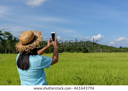 Asian woman shooting landscape of rice field.