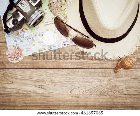 Travel concept with digital camera, straw hat, sunglasses, world map, compass and seashell on wooden table