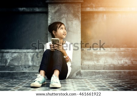 Asian kid girl imagine to the future while playing the mobile smart phone.
