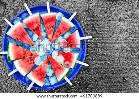 Slice of watermelon with ice cubes on a black background. Ice cream with the taste of watermelon. Sweet dessert. The summer mood.