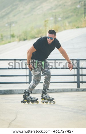 young man with inline skates ride in summer park outdoor roller skater