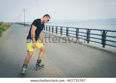 young man with inline skates ride in summer park seafront outdoor roller skater