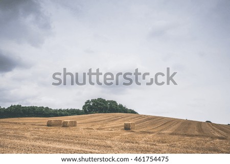 Cloudy weather over a field with hay bales