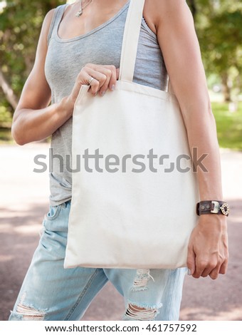 Woman holding empty canvas bag outdoor. Template mock up