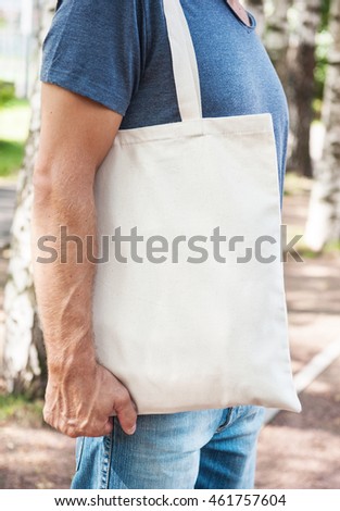 Man holding empty canvas bag outdoor. Template mock up