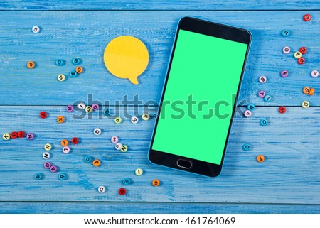 Social Media Chat, tablet on office table desk with blank green screen. Live chat yellow bubble on blue wooden background. Top view and copy space for text.