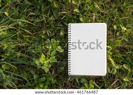 White blank open notepad book on grass green background with office supplies. Education business backdrop for your ad text, e-learning, making notes 