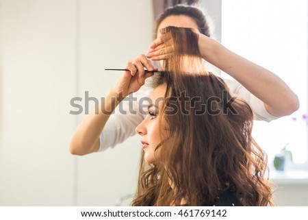 Hairdresser doing hair style for woman. Concept of fashion and beauty Royalty-Free Stock Photo #461769142