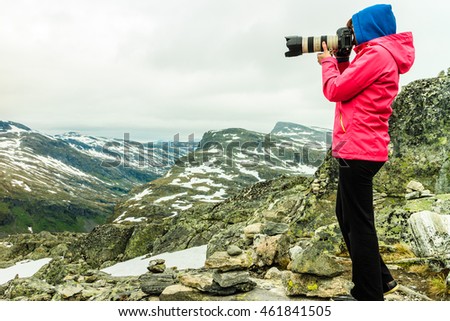 Tourism vacation and travel. Female tourist taking photo with camera, enjoying mountains landscape from Dalsnibba viewpoint, Norway Scandinavia.