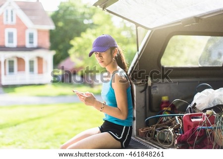 Portrait of teenage girl, sitting on open car boot