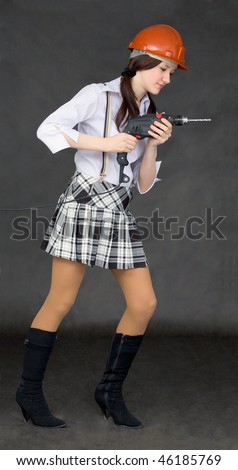 Female student learns to use power tools on black background