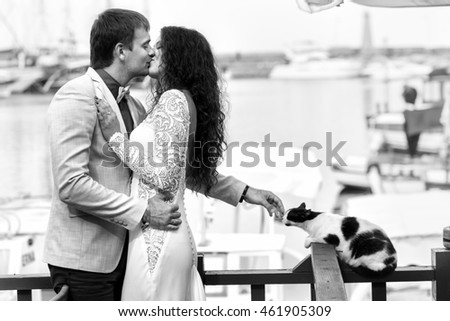 Black and white picture of man stroking cat while woman kisses him