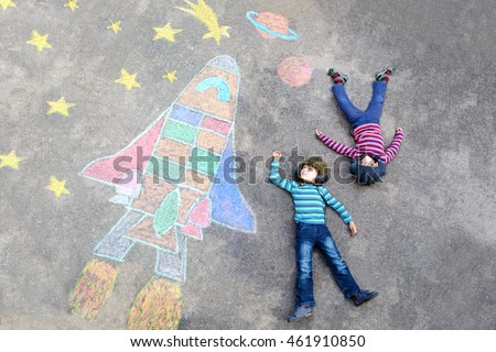 Two Funny little kid boys flying in universe by a space shuttle picture painting with colorful chalks. Creative leisure for children outdoors in summer. Friends having fun together Royalty-Free Stock Photo #461910850