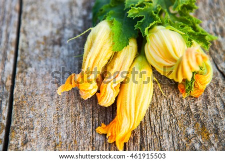 Zucchini flowers on a old wooden table close up, rustic style, selective focus
