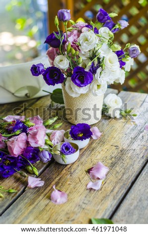 Beautiful bunch of white and purple roses in a vase on a wooden table.