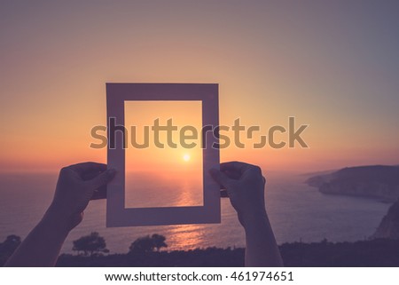 Inspirational photo frame on blurred beach background. Travel summer sunset concept. Moody sky with white photo frame. Instagram filter effect used.