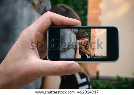 young beautiful happy girl, posing in front of a photographer. photo on the phone, the person photographed on a smartphone from the side. tuuch. selfie