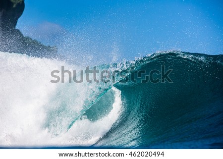 Shorebreak Big ocean wave near rocky coast in daylight. Beautiful sky with clouds. Sea Water surface for surfing sport. Nobody on picture. Vibrant bright tropical colorful image.