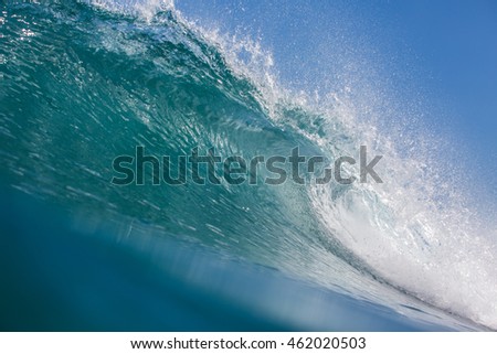 Shorebreak ocean wave in daylight. Beautiful sky with clouds. Sea Water surface for surfing sport. Nobody on picture. Vibrant bright tropical colorful image.