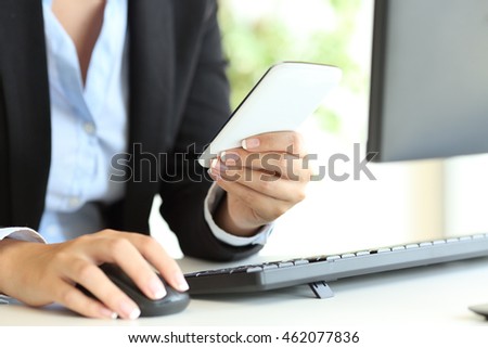 Close up of a businesswoman hands using a desktop computer mouse and smart phone on line at office
