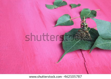 Buddha and Bodhi leaf on wooden pink.copy space