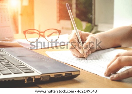 Business man Writing payments and using Laptop on desk vintage style
