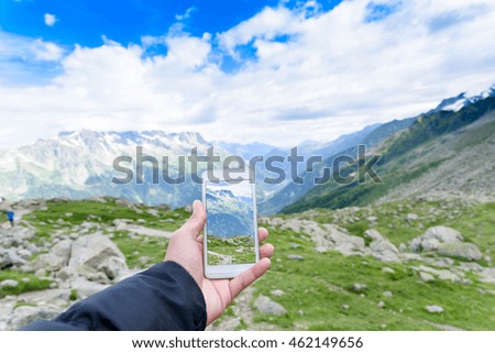 Hand holding smartphone taking photo of Aiguile du Chardonnet a beautiful view of Mont Blanc Massif , Chamonix France, Europe