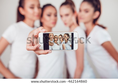 Positive friends portrait of four happy girls making selfie, sure funny faces, grimaces, joy, emotions, casual style, pastel colors, white wall. crazy funny woman. White background.