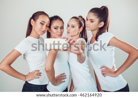 Positive friends portrait of four happy girls making selfie, sure funny faces, grimaces, joy, emotions, casual style, pastel colors, white wall. crazy funny woman. White background.