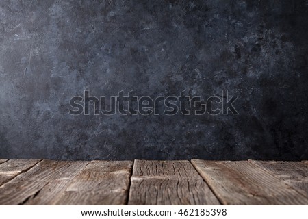 Old wooden table in front of black chalkboard wall for your text. View with copy space