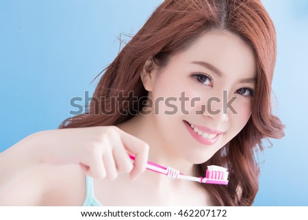 Beautiful young woman with health teeth and charming smile.holding the tooth brush, Isolated over blue background, asian beauty